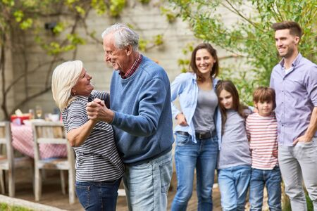 150512914 i nonni felici ballano il valzer davanti alla famiglia durante una celebrazione in giardino